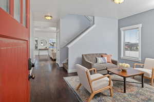 Living area featuring stairs, baseboards, and wood finished floors