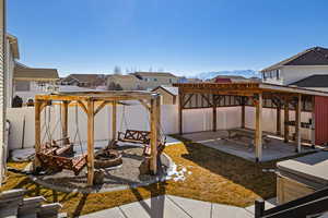 View of patio featuring a hot tub, a mountain view, a pergola, a fenced backyard, and a fire pit