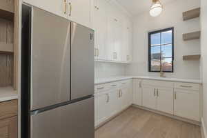 Kitchen featuring open shelves, light countertops, decorative backsplash, freestanding refrigerator, and a sink