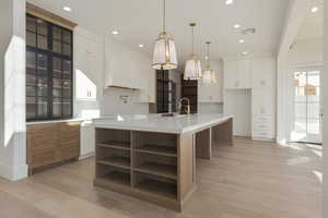 Kitchen with visible vents, light wood-style flooring, custom exhaust hood, light countertops, and open shelves