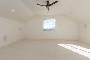 Additional living space with light carpet, visible vents, baseboards, ceiling fan, and vaulted ceiling