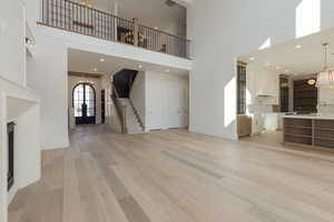 Unfurnished living room with baseboards, stairway, an inviting chandelier, light wood-style floors, and a sink