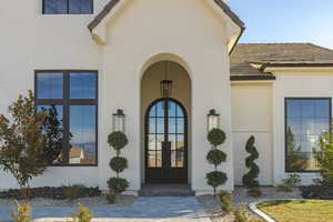 Doorway to property with brick siding, a tiled roof, and stucco siding