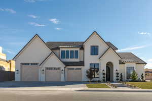 View of front of home with a garage, decorative driveway, and stucco siding