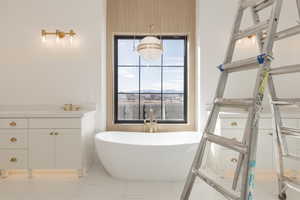 Bathroom featuring marble finish floor, a freestanding tub, and vanity