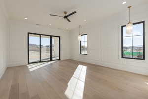 Empty room with light wood finished floors, a wealth of natural light, and a decorative wall