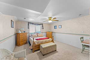 Carpeted bedroom with wallpapered walls, ceiling fan, visible vents, and baseboards