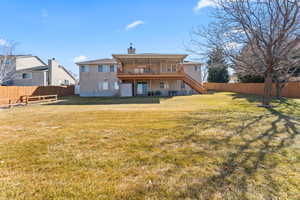 Rear view of house featuring a fenced backyard, a chimney, stairway, and a lawn