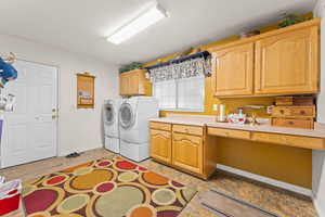 Laundry room with cabinet space, baseboards, and separate washer and dryer