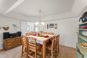 Dining room featuring baseboards, a fireplace, a raised ceiling, and light colored carpet