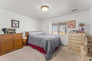 Bedroom with light carpet, visible vents, and baseboards