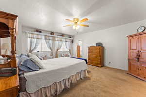 Bedroom featuring light carpet, baseboards, a ceiling fan, and a textured ceiling