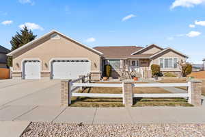 Ranch-style home with a garage, driveway, a fenced front yard, and brick siding