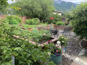 View of yard with an outdoor fire pit, a garden, fence, and a mountain view