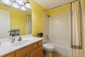 Bathroom featuring visible vents, toilet, shower / tub combo, vanity, and tile patterned floors