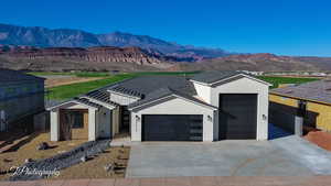 View of front of property with a mountain view, driveway, an attached garage, and stucco siding