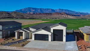 View of front of house with a garage, driveway, a mountain view, and stucco siding