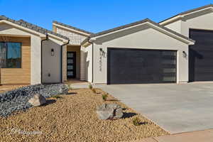 View of front of home featuring an attached garage, driveway, stone siding, a tiled roof, and stucco siding