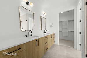 Full bathroom featuring double vanity, a sink, visible vents, and a walk in closet