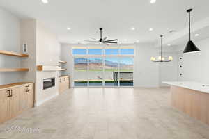 Unfurnished living room with recessed lighting, visible vents, a glass covered fireplace, and ceiling fan with notable chandelier