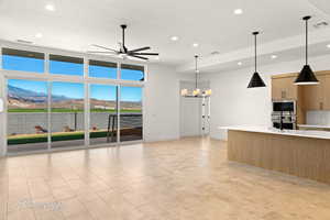 Kitchen featuring visible vents, modern cabinets, appliances with stainless steel finishes, light countertops, and ceiling fan with notable chandelier