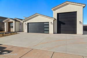 View of front of property featuring a garage, a tile roof, and stucco siding