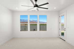 Empty room featuring a mountain view, recessed lighting, light carpet, visible vents, and a ceiling fan