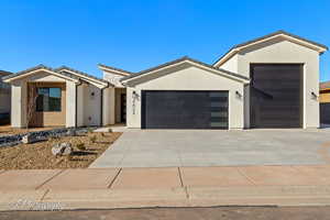 View of front of home with a tiled roof, concrete driveway, an attached garage, and stucco siding