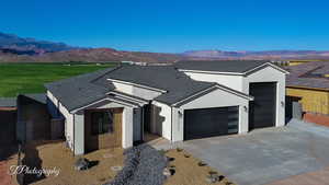 View of front facade with a garage, concrete driveway, a mountain view, and stucco siding