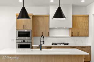 Kitchen with appliances with stainless steel finishes, backsplash, and pendant lighting