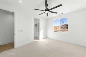 Unfurnished bedroom featuring visible vents, baseboards, a closet, carpet, and a walk in closet