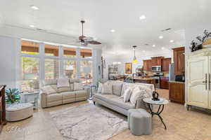 Living room featuring visible vents, ceiling fan with notable chandelier, ornamental molding, and recessed lighting