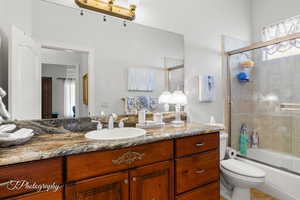 Bathroom with toilet, combined bath / shower with glass door, and vanity