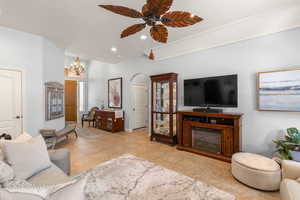 Living area with recessed lighting, tile patterned flooring, arched walkways, and ceiling fan with notable chandelier