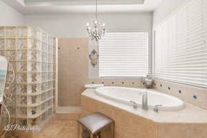 Bathroom featuring a chandelier, plenty of natural light, a bath, and a walk in shower