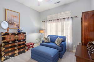 Living area with carpet, visible vents, ceiling fan, and baseboards