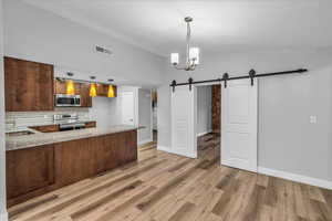 Kitchen featuring a barn door, visible vents, a sink, stainless steel appliances, and backsplash