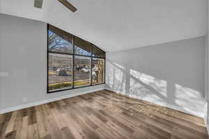 Spare room with a wealth of natural light, a textured ceiling, baseboards, and wood finished floors