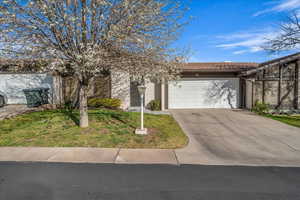 View of front of house with a front yard, concrete driveway, a tiled roof, and an attached garage