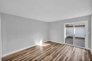 Unfurnished bedroom with access to exterior, baseboards, and wood finished floors