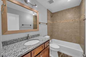 Full bath with visible vents, toilet, wood finished floors,  shower combination, and vanity