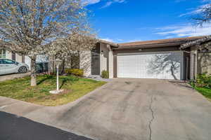 View of front facade featuring a garage, driveway, and a front lawn