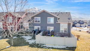 Back of house featuring fence private yard, stone siding, and a lawn