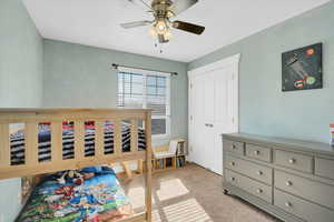 Bedroom featuring a ceiling fan, a closet, and light colored carpet