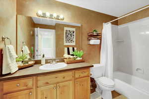 Full bath with toilet, shower / bath combo with shower curtain, and vanity