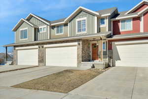 View of front of home with board and batten siding, concrete driveway, stone siding, and a garage