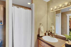 Full bath with a shower with curtain and vanity