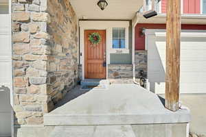 View of exterior entry with stone siding and an attached garage