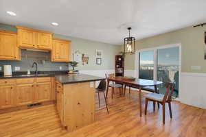 Kitchen with a wainscoted wall, light wood finished floors, a sink, and light brown cabinetry