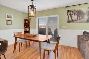 Dining space featuring an inviting chandelier, wood finished floors, and wainscoting